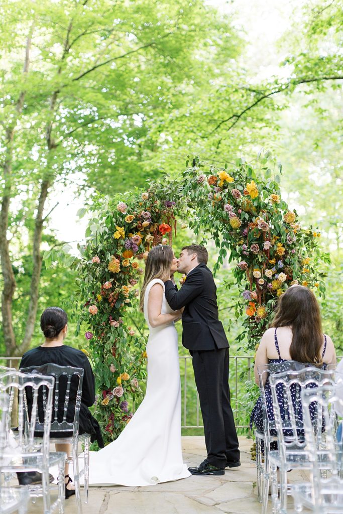 Bride and Groom kissing under Wedding Floral Arch at The Milky Way House Wedding Venue in Knoxville, TN. 